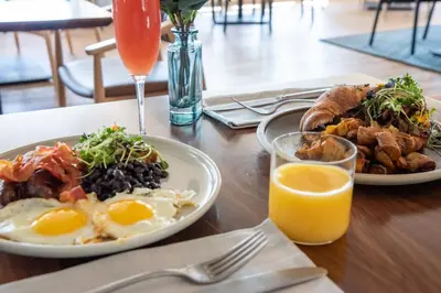 two plates of breakfast food on a table with orange juice at The Crimson Jasper in Jasper