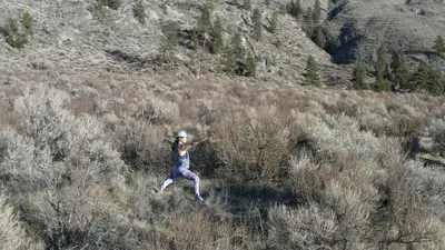 a woman is running in a field of brush at Spirit Ridge, in The Unbound Collection by Hyatt in Osoyoos