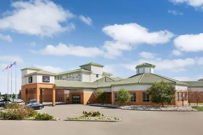 a large building with a car parked in a parking lot at Royal Hotel Edmonton Airport Trademark Collection By Wyndham in Leduc