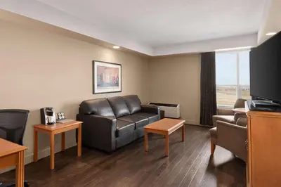 a living room with a leather couch and a tv at Royal Hotel Edmonton Airport Trademark Collection By Wyndham in Leduc