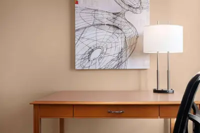 a desk with a lamp and a painting on the wall at Royal Hotel Edmonton Airport Trademark Collection By Wyndham in Leduc