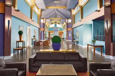 a lobby with a couch and a plant in the middle at Royal Hotel Edmonton Airport Trademark Collection By Wyndham in Leduc