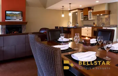 a dining room with a table with wine glasses on it at Bellstar Suites at Solara Resort in Canmore