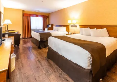 a hotel room with two beds and a television at Canmore Inn & Suites in Canmore