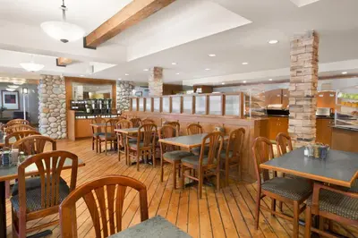 a restaurant with wooden tables and chairs and a bar at Canmore Inn & Suites in Canmore