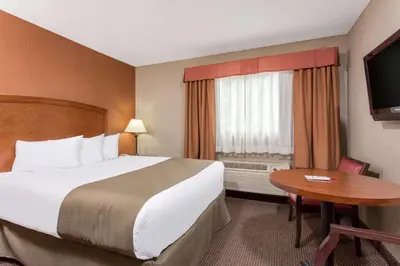 a hotel room with a large bed and a table at Canmore Inn & Suites in Canmore