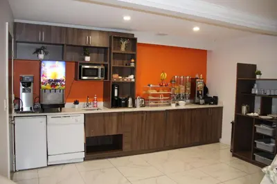 a large kitchen with orange walls and a counter at Howard Johnson by Wyndham Downtown Kamloops in Kamloops
