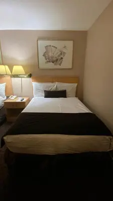 a large bed in a hotel room with two lamps at Howard Johnson by Wyndham Downtown Kamloops in Kamloops