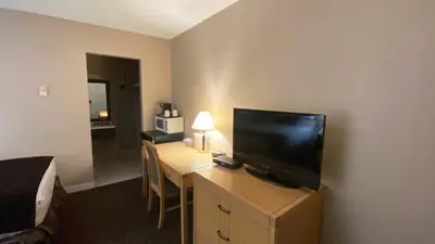 a room with a desk with a television and a bed at Howard Johnson by Wyndham Downtown Kamloops in Kamloops