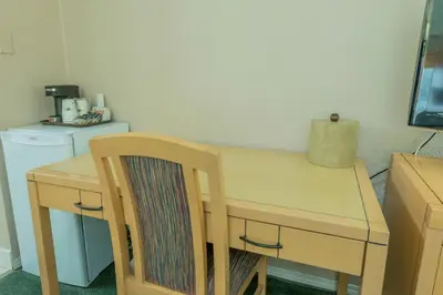 a wooden table with a wooden chair next to a kitchen at Howard Johnson by Wyndham Downtown Kamloops in Kamloops
