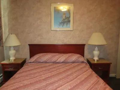 a bedroom with a bed and two night stands with lamps at Tropicana Suite Hotel in Vancouver
