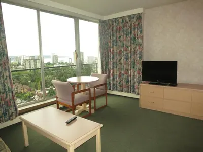 a living room with a table and a tv and windows at Tropicana Suite Hotel in Vancouver