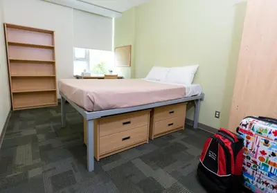 a bedroom with a bed in a room with a backpack at University of Calgary Accommodations and Events in Calgary