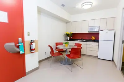 a small kitchen with a table and red chairs at University of Calgary Accommodations and Events in Calgary