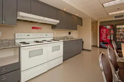 a kitchen with white appliances and gray cabinets at Residence & Conference Centre - Kamloops in Kamloops