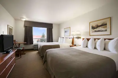 a hotel room with two beds and a television at Super 8 by Wyndham Slave Lake AB in Slave Lake