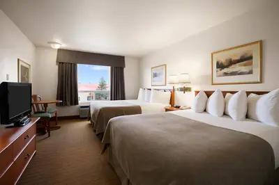 a hotel room with two beds and a flat screen tv at Super 8 by Wyndham Slave Lake AB in Slave Lake