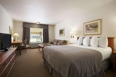 a hotel room with a large bed and a television at Super 8 by Wyndham Slave Lake AB in Slave Lake