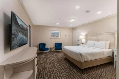 a hotel room with a bed and two blue chairs at Prestige Beach House, WorldHotels Crafted in Kelowna