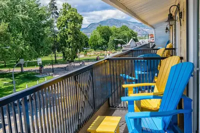 two blue and yellow chairs on a balcony with a view at Prestige Beach House, WorldHotels Crafted in Kelowna