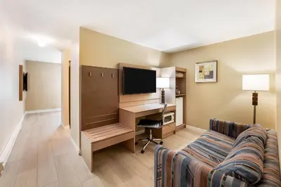 a hotel room with a desk with a computer and a couch at Days Inn by Wyndham Nanaimo in Nanaimo