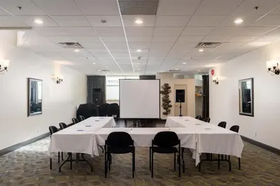a conference room with tables and chairs and a whiteboard at Ocean Promenade Hotel in White Rock