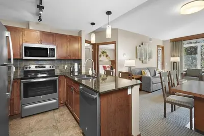 a kitchen with stainless steel appliances and a living room at Mountain View Escape with open hot tub, Views!! in Canmore