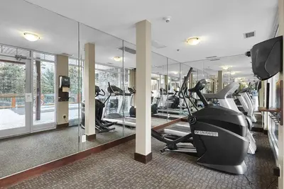 a gym with treadmills and ellipticals in a building at Mountain View Escape with open hot tub, Views!! in Canmore