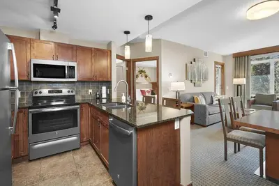 a kitchen with stainless steel appliances and a living room at Mountain View Escape with open hot tub, Views!! in Canmore