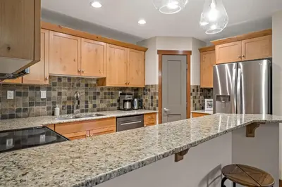 a kitchen with wooden cabinets and a granite counter top at RidgeView Loft - Top Floor 2 Bed 2 Bath, Amazing Views in Canmore