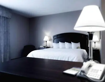 a hotel room with a bed and a phone on a table at Hampton Inn & Suites by Hilton Edmonton International Airport in Leduc