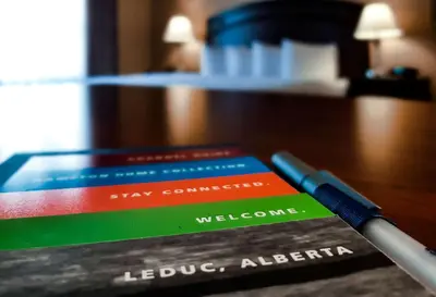 a group of books sitting on a table with a pen at Hampton Inn & Suites by Hilton Edmonton International Airport in Leduc