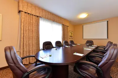 a conference room with a table and chairs and a screen at Hampton Inn & Suites by Hilton Edmonton International Airport in Leduc