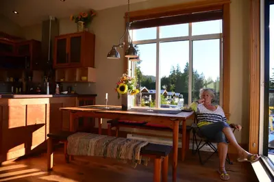 a woman sitting at a table in a kitchen at Bjørn Holm in Port Renfrew