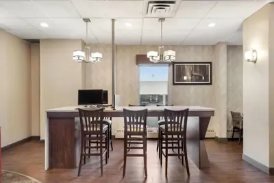 a kitchen with a bar with chairs and a desk at Days Inn by Wyndham Airdrie in Airdrie