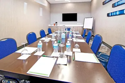 a conference room with a long table and blue chairs at Holiday Inn Hotel & Suites - Calgary Airport North by IHG in Calgary
