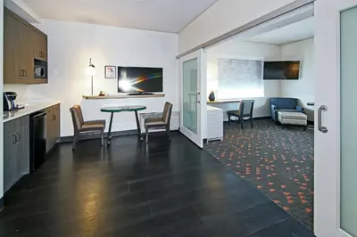 a kitchen and a living room with a table and chairs at Holiday Inn Hotel & Suites - Calgary Airport North by IHG in Calgary