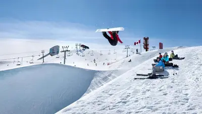 a snowboarder jumping off a ramp at a ski slope at Amenida Residences, Calgary in Calgary