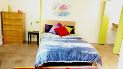 a bedroom with a bed with colorful pillows on it at U of A Homestay, Trails & Whyte Ave in Edmonton