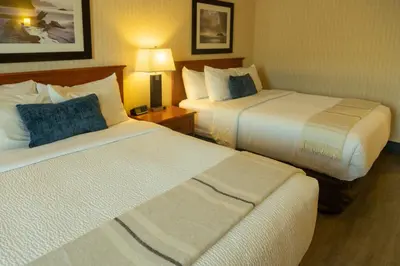 a hotel room with two beds and a lamp at Inn on Long Lake in Nanaimo