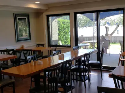 a restaurant with wooden tables and chairs and windows at Inn on Long Lake in Nanaimo