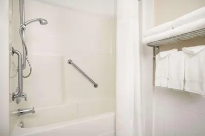 a white bathroom with a shower and a tub at Days Inn & Suites by Wyndham Langley in Langley