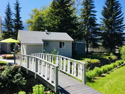 a wooden bridge over a garden with a house at Brookside Motel in Golden