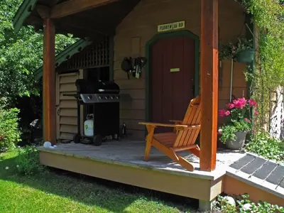 a porch of a house with a bench and a grill at Summerhill Guest House in Tofino