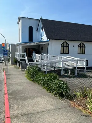 a white building with a white fence in front of it at Char's Landing Hostel in Port Alberni