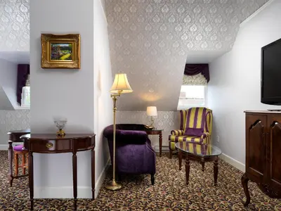 a hotel room with a tv and a table and chairs at Pendray Inn and Tea House in Victoria