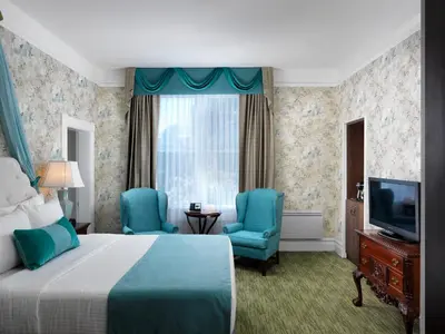 a hotel room with a bed and two chairs and a television at Pendray Inn and Tea House in Victoria