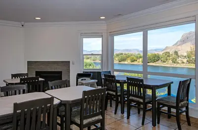 a dining room with tables and chairs and a fireplace at Riverland Inn & Suites in Kamloops