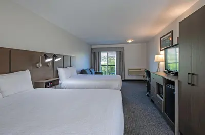 a hotel room with two beds and a flat screen tv at Riverland Inn & Suites in Kamloops