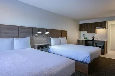 a hotel room with two beds and a kitchen at Riverland Inn & Suites in Kamloops